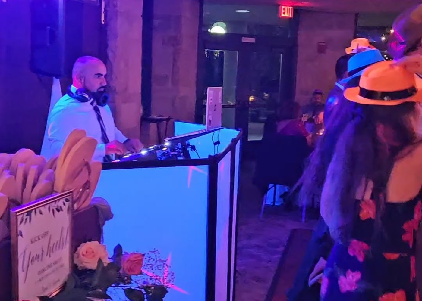 Alex mixing at the white booth with party guests wearing hats