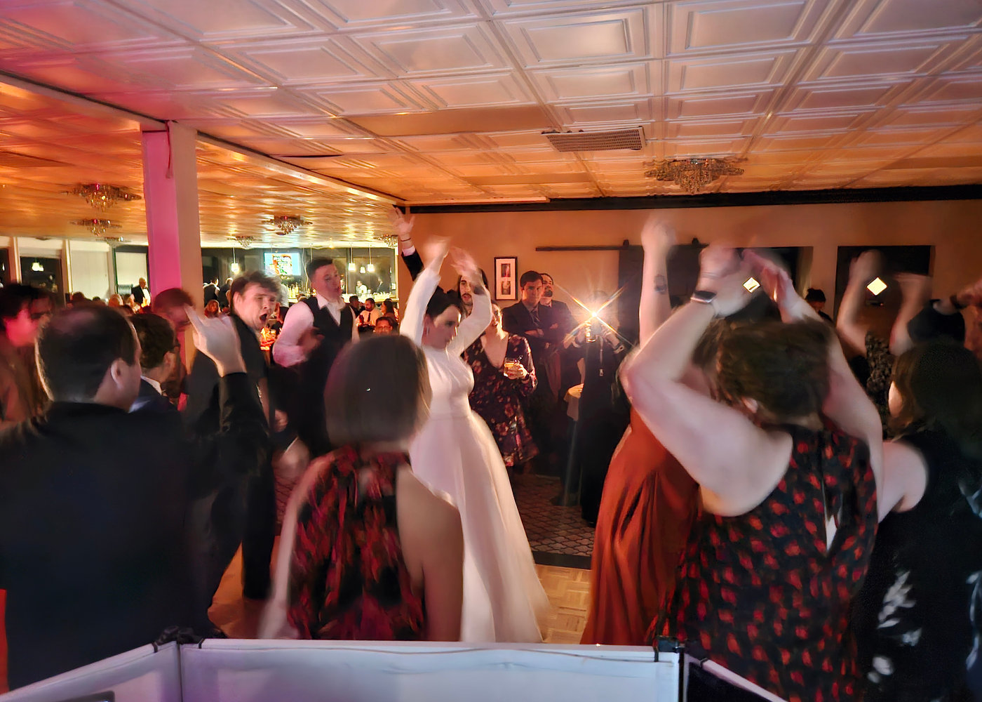 Bride dancing with her arms up among wedding guests