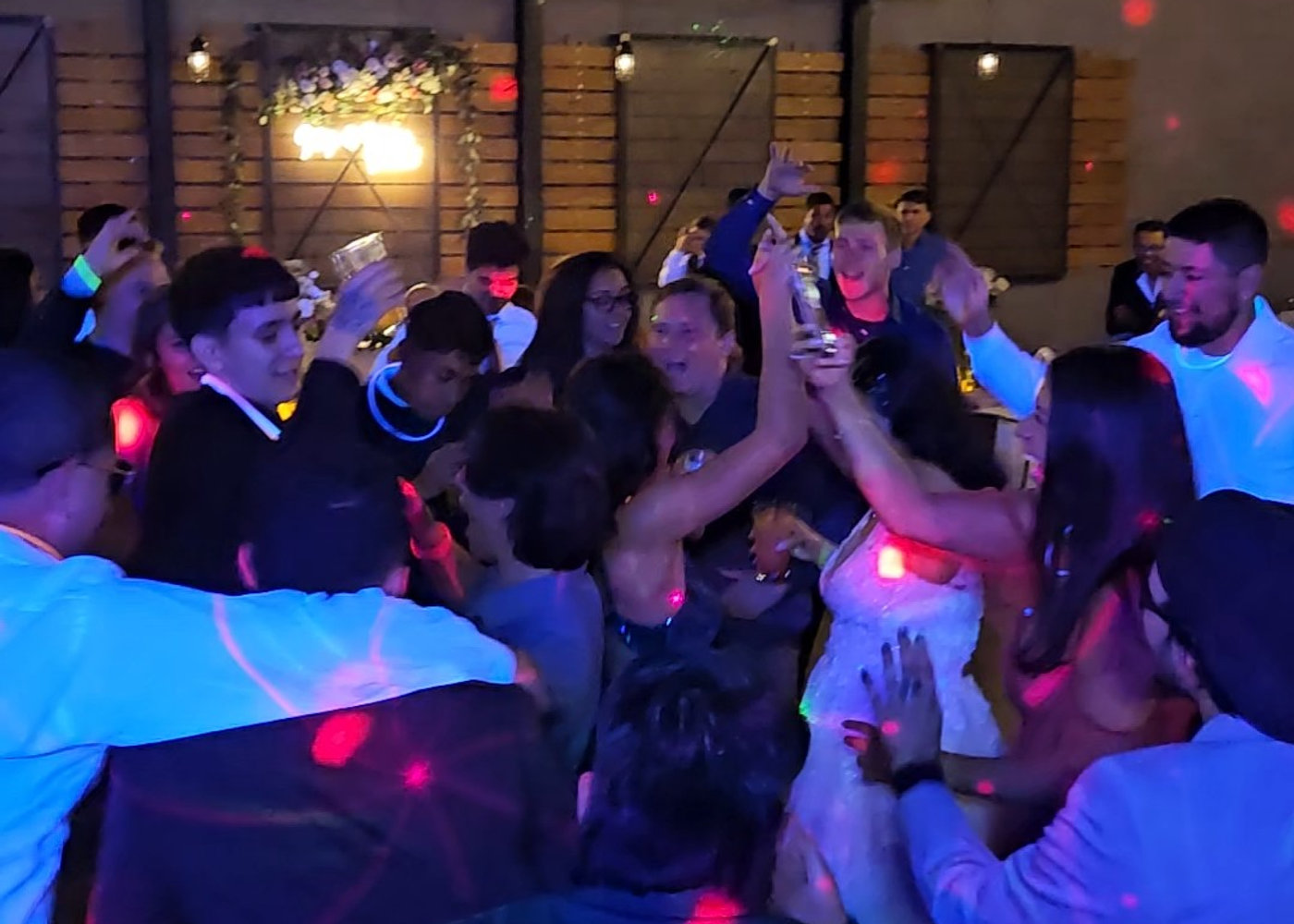 Guests with their hands up around the bride on the dance floor